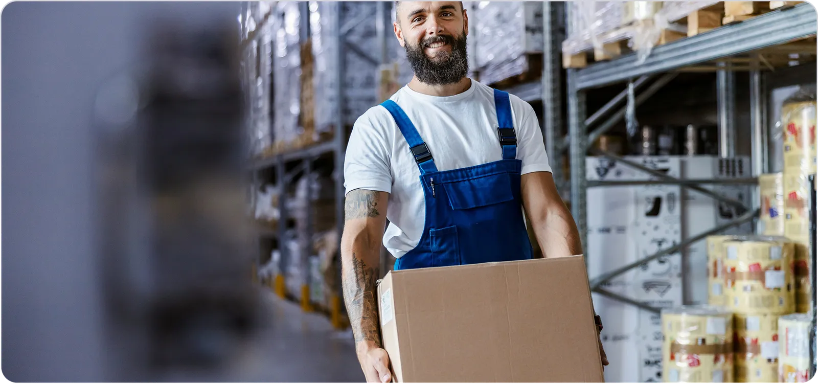 Warehouse worker carrying box in food and drink storage facility